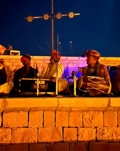 Manganiyar musicians performing on a lit stone stage at night
