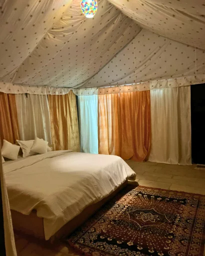 Inside a Swiss tent: a big bed, colourful curtains and a rug