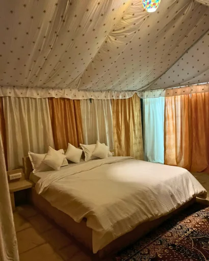 Tent interior with canopy bed, lanterns and Rajasthani rug