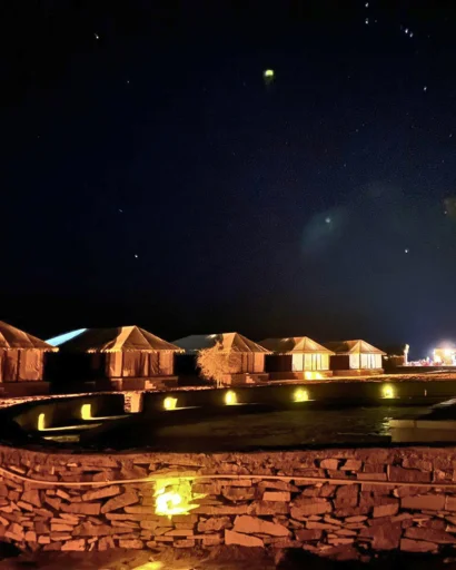 Camp tents and lit pathways under a starry night sky