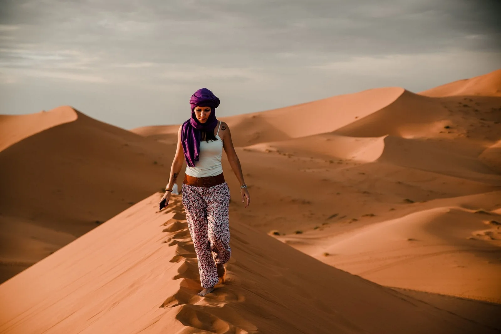 Traveller walking along a dune ridge in a headscarf
